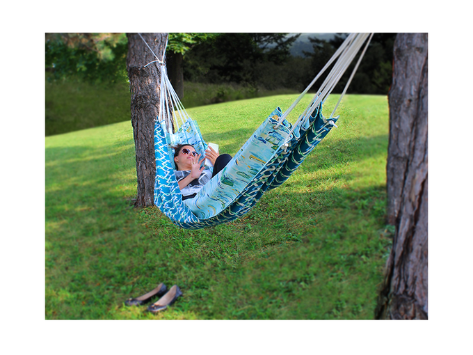 Female adult lying in a hammock while swiping on a tablet